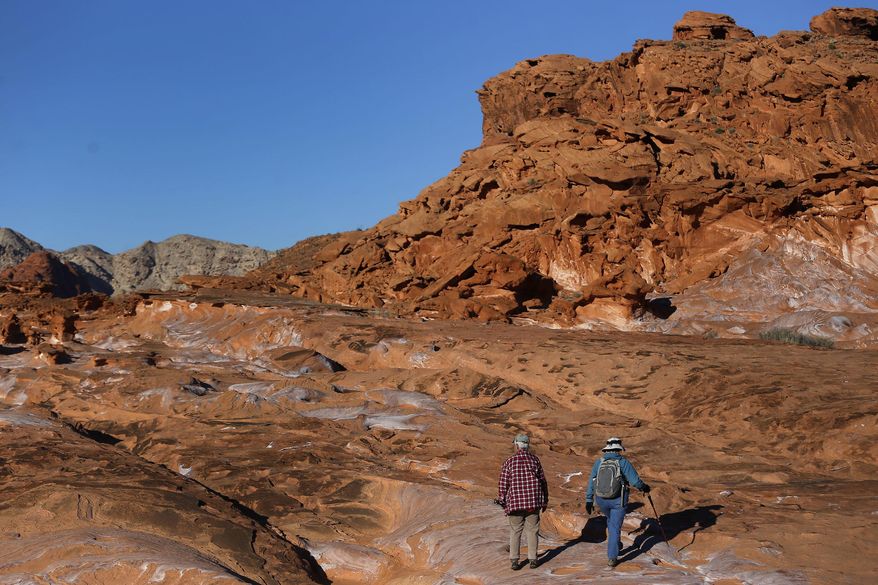 In this Jan. 17, 2017 photo, visitors hike at Gold Butte National Monument in Gold Butte, Nev. At Nevada's newest national monument, you can hike through twisted sandstone sculptures, tour outdoor galleries of ancient rock art, explore a historic ghost town and stare down the Devil's Throat. (Christian K. Lee/Las Vegas Review-Journal via AP)