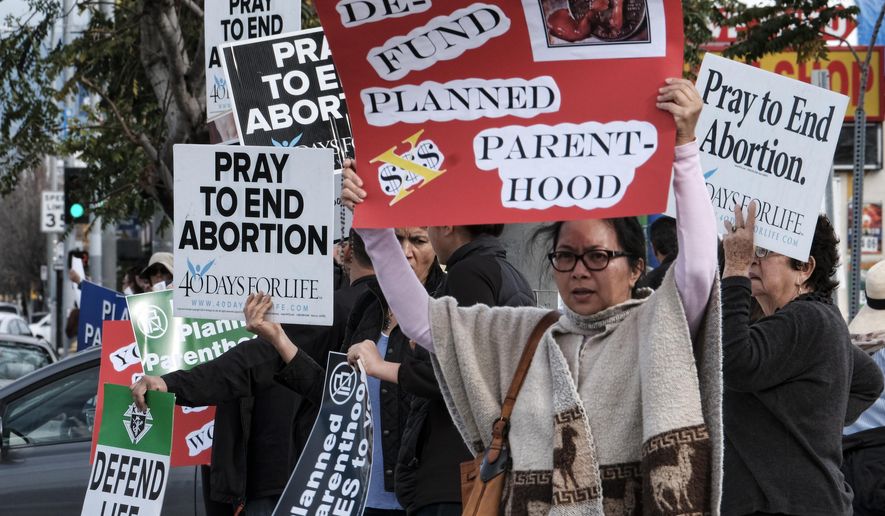 Protesters carry signs outside a Planned Parenthood health center in the Van Nuys section of Los Angeles on Saturday, Feb. 11, 2017. Several dozen protesters gathered in California's San Fernando Valley demanding the organization be stripped of its federal funding. (AP Photo/Richard Vogel)