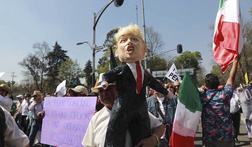 A woman holds a pinata depicting U.S. President Donald Trump during a march demanding respect for Mexico and its migrants, in the face of perceived hostility from the Trump administration, in Mexico City, Sunday, Feb 12, 2017. About 20,000 people, many dressed in white, some carried Mexican flags, as a sign of unity. (AP Photo/Christian Palma)