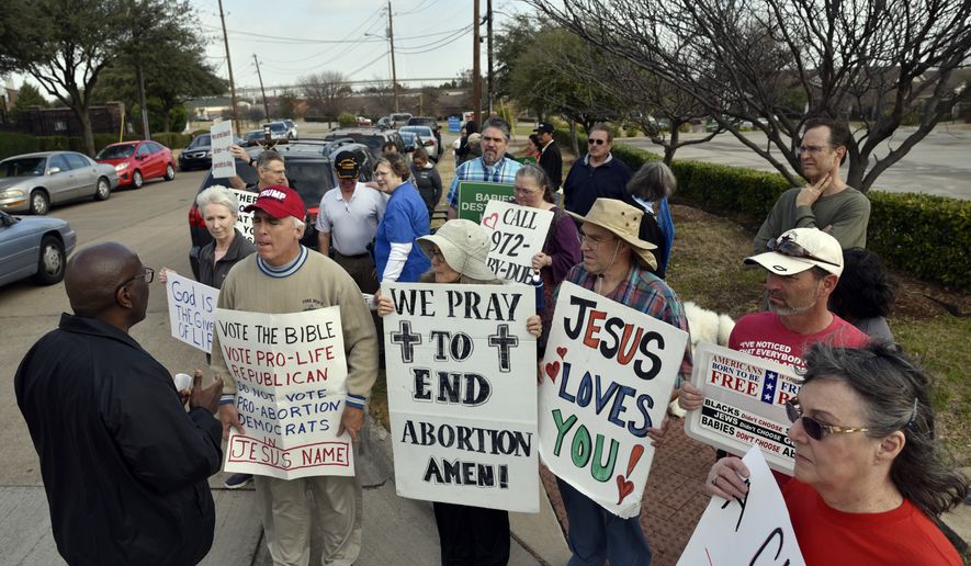 Dallas Police Sgt. Hall, left, speaks with Rives Grogan, 51, of Mansfield, Texas, who wears a red Trump cap, and other anti-abortion protesters, informing them which sidewalks they can use to conduct their protest, outside of the Planned Parenthood South Dallas Surgical Health Services Center, Saturday morning, Feb. 11, 2017, in Dallas. (Ben Torres/The Dallas Morning News via AP) ** FILE **