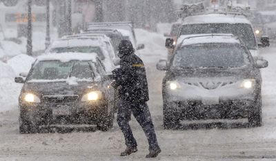 A pedestrian crosses the street in front of vehicles during a snowstorm, Sunday, Feb. 12, 2017, in Waltham, Mass. (AP Photo/Steven Senne)