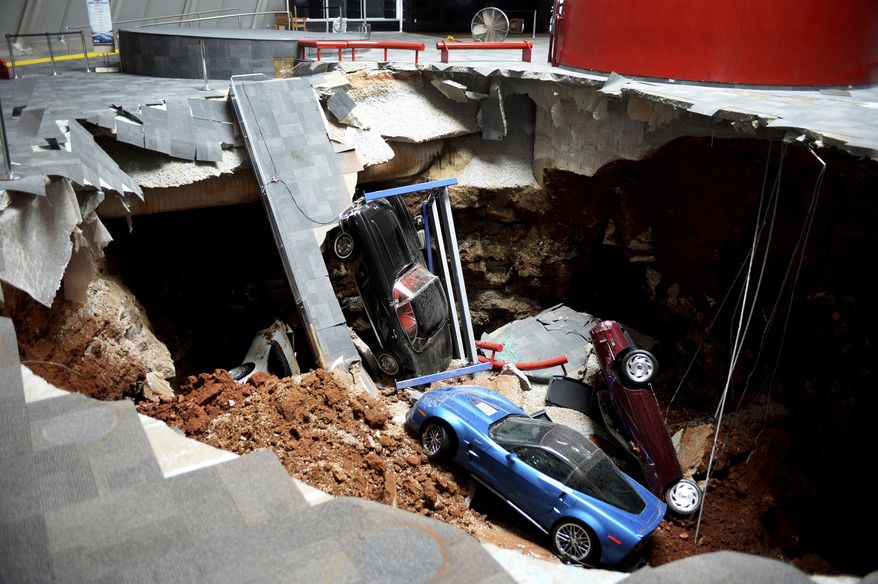 FILE - In this Feb. 12, 2014, file photo, cars lie in a sinkhole that opened up at the Skydome showroom in the National Corvette Museum in Bowling Green, Ky. The museum said a prized Corvette still covered in dirt and debris from its 2014 fall into the sinkhole has been moved from display to undergo repairs. The museum said the restoration work on the 1962 Corvette will be done at the museum and visitors will be able to watch the progress in restoring the car. (AP Photo/Michael Noble Jr., File)