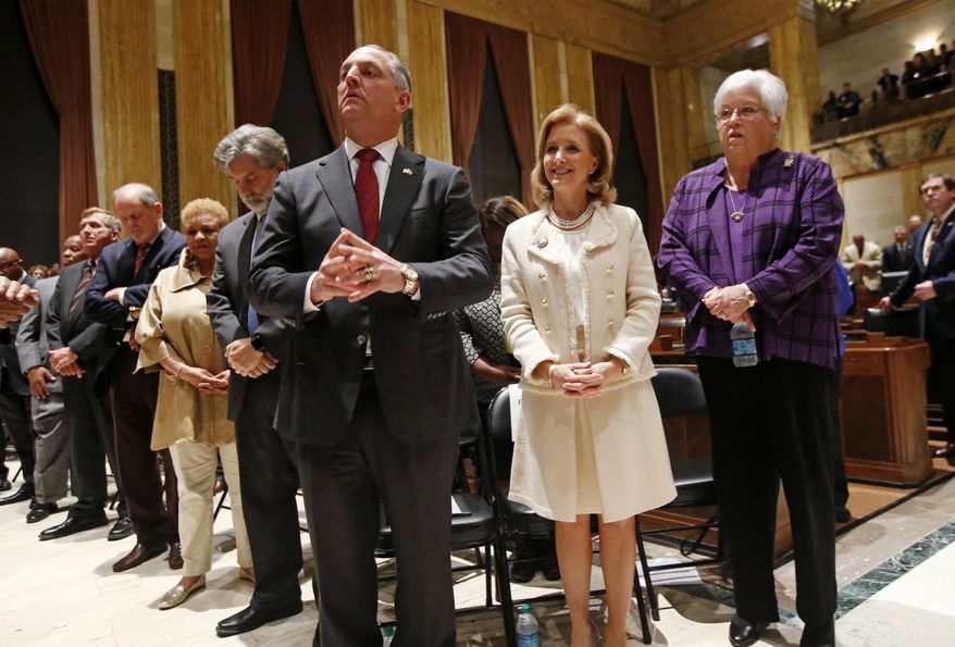 Louisiana Gov. John Bel Edwards, center listens to the invocation with his wife Donna Edwards and former campaign manager Linda Day, right, at the opening of a special session of the state legislature in Baton Rouge, La., Monday, Feb. 13, 2017. (AP Photo/Gerald Herbert, Pool)