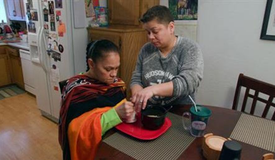 This image released by Twin Cities PBS shows Daisy Duarte, right, caring for her mother Sonia, who was diagnosed with a genetic form of early-onset Alzheimer’s, in a scene from the PBS documentary, “Alzheimer’s: Every Minute Counts.” (Twin Cities PBS via AP)