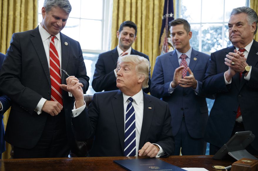 President Donald Trump hands a pen to Rep. Bill Huizenga, R-Mich., after signing House Joint Resolution 41 in the Oval Office of the White House in Washington, Tuesday, Feb. 14, 2017. From left are, Huizenga, Trump, House Speaker Paul Ryan of Wis., Rep. Sean Duffy, R-Wis., and Rep. Peter King, R-N.Y. (AP Photo/Evan Vucci)