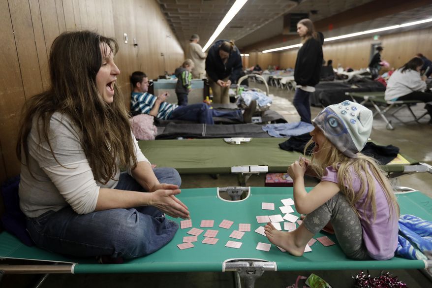 Katherine Boeger Knight, left, plays a card game with her daughter Amethyst, 5, at a shelter for evacuees from cities surrounding the Oroville Dam, Monday, Feb. 13, 2017, in Chico, Calif. The thousands of people who were ordered to leave their homes after a damaged California spillway threatened to unleash a 30-foot wall of water may not be able to return until significant erosion is repaired, authorities said Monday. (AP Photo/Marcio Jose Sanchez)