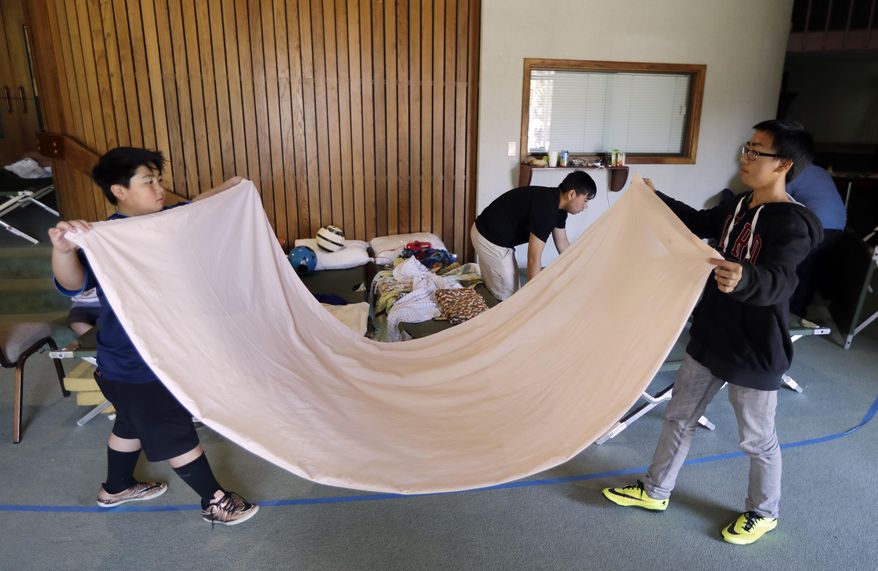 Brandon Moua, left, and his brother Justin, of Oroville, Calif., fold a blanket as they prepared to leave a shelter Tuesday, Feb. 14, 2017, in Chico, Calif. Authorities lifted an evacuation order Tuesday for thousands of California residents who live below the nation's tallest dam after declaring that the risk of catastrophic collapse of a damaged spillway had been significantly reduced. (AP Photo/Marcio Jose Sanchez)