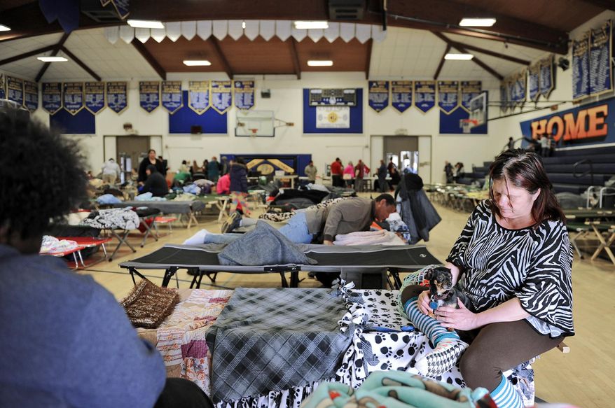 Evacuee Lisa Nelson, right, relaxes with her dog at an emergency shelter set up at the Sutter High School gymnasium on Monday, Feb. 13, 2017, in Sutter, Calif. The thousands of people who were ordered to leave their homes after a damaged California spillway threatened to unleash a 30-foot wall of water may not be able to return until significant erosion is repaired, authorities said Monday. (Chris Kaufman/The Appeal-Democrat via AP)