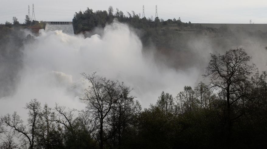 In this Monday Feb. 13, 2017 photo, mist forms as water flows down Oroville Dam's main spillway near Oroville, Calif. Officials have ordered residents near the Oroville Dam in Northern California to evacuate the area Sunday, Feb. 12, saying a "hazardous situation is developing" after an emergency spillway severely eroded. (Bill Husa/The Chico Enterprise-Record via AP)