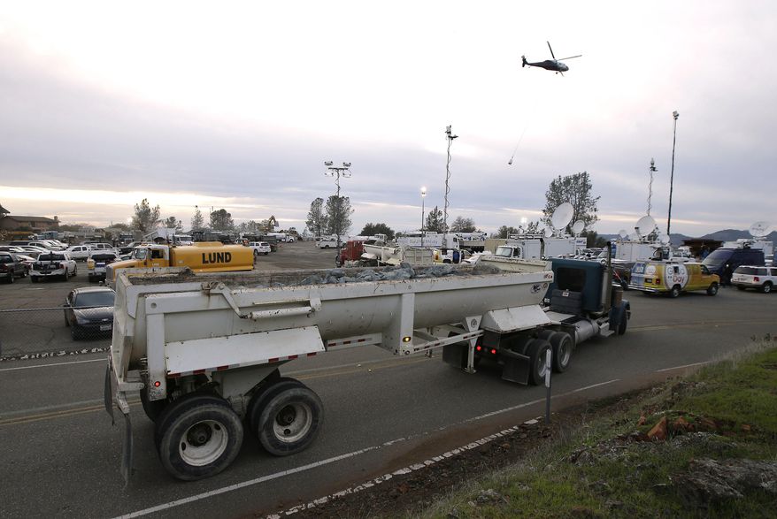 A truck loaded with rocks arrives at the staging area as a helicopter takes off with a bag filled with rocks to be dropped on a hole on the lip of the Oroville Dam's emergency spillway Monday Feb., 13, 2017, in Oroville, Calif. The barrier, at the nation's tallest dam, is being repaired a day after authorities ordered mass evacuations for everyone living below the lake out of concerns the spillway could fail. (AP Photo/Rich Pedroncelli)