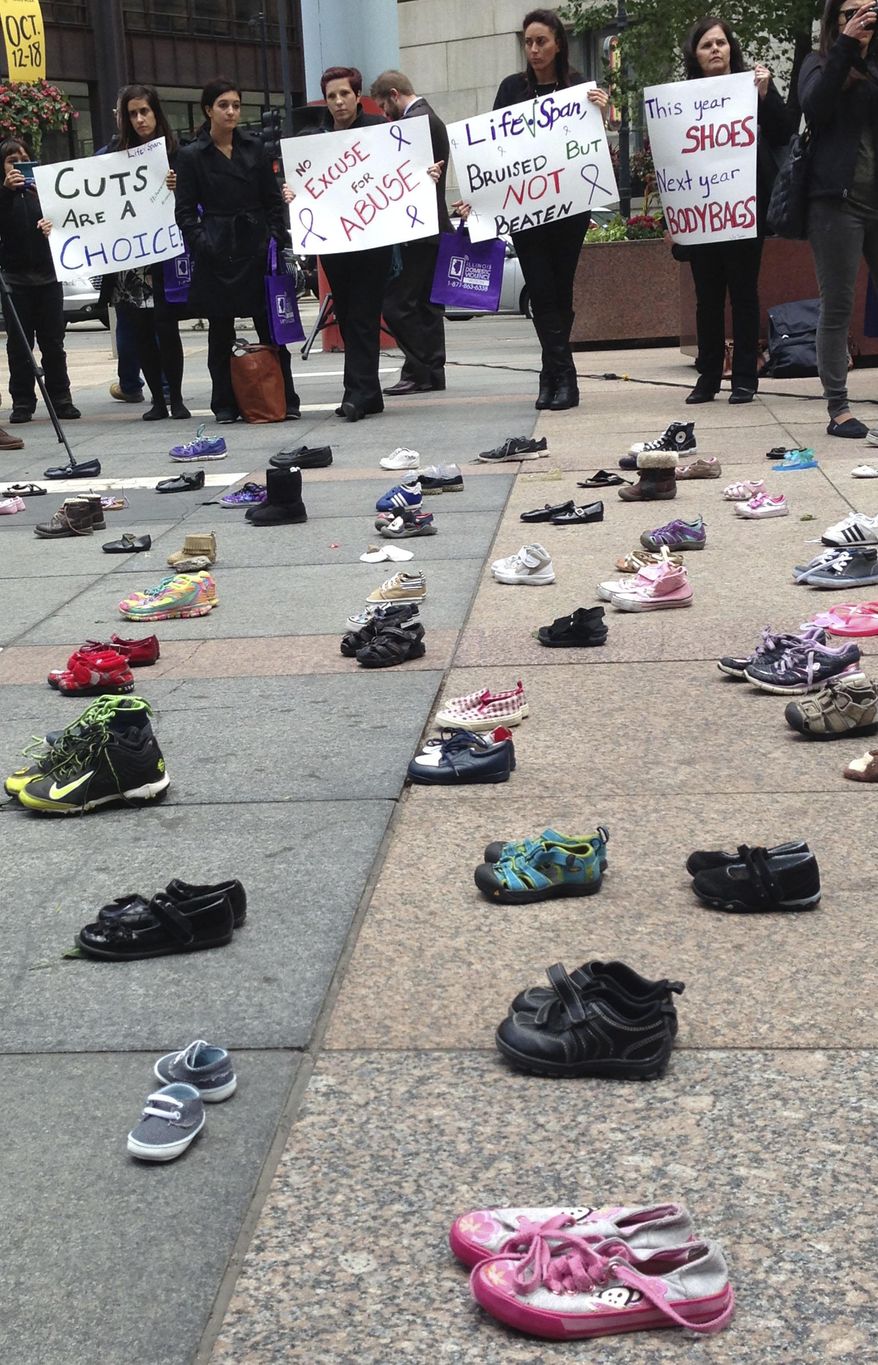 FILE - In this Oct. 1, 2015 file photo, advocates for victims of domestic abuse protest outside of state offices in downtown Chicago. The Illinois Department of Human Services waited five months to inform dozens of domestic violence shelters there was no money for them in a temporary budget lawmakers approved last summer. Officials providing services to victims of domestic violence tell The Associated Press they were unaware that about $9 million in state funding was left out of the stopgap plan that expired in December. (AP Photo/Sophia Tareen)