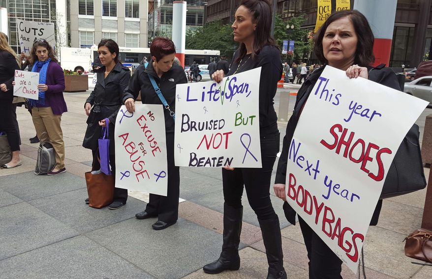 FILE - In this Oct. 1, 2015 file photo, advocates for victims of domestic abuse protest outside of state offices in downtown Chicago. The Illinois Department of Human Services waited five months to inform dozens of domestic violence shelters there was no money for them in a temporary budget lawmakers approved last summer. Officials providing services to victims of domestic violence tell The Associated Press they were unaware that about $9 million in state funding was left out of the stopgap plan that expired in December. (AP Photo/Sophia Tareen, File)
