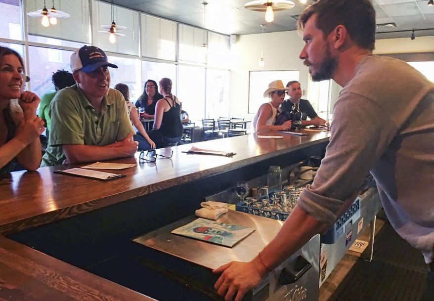 In this Sept. 17, 2016 photo, Austin Wiley, right, owner of Spangalang Brewery, talks to patrons at the bar in Denver's Five Points neighborhood. The historic black neighborhood was often called "The Harlem of West," a place where Billie Holiday, Count Basie and Miles Davis performed and novelist Jack Kerouac tried to capture the spirit of the bebop movement in "On The Road." The brewery's name, Spangalang, is the term used to describe the bread and butter jazz cymbal rhythm. (AP Photo/Russell Contreras)