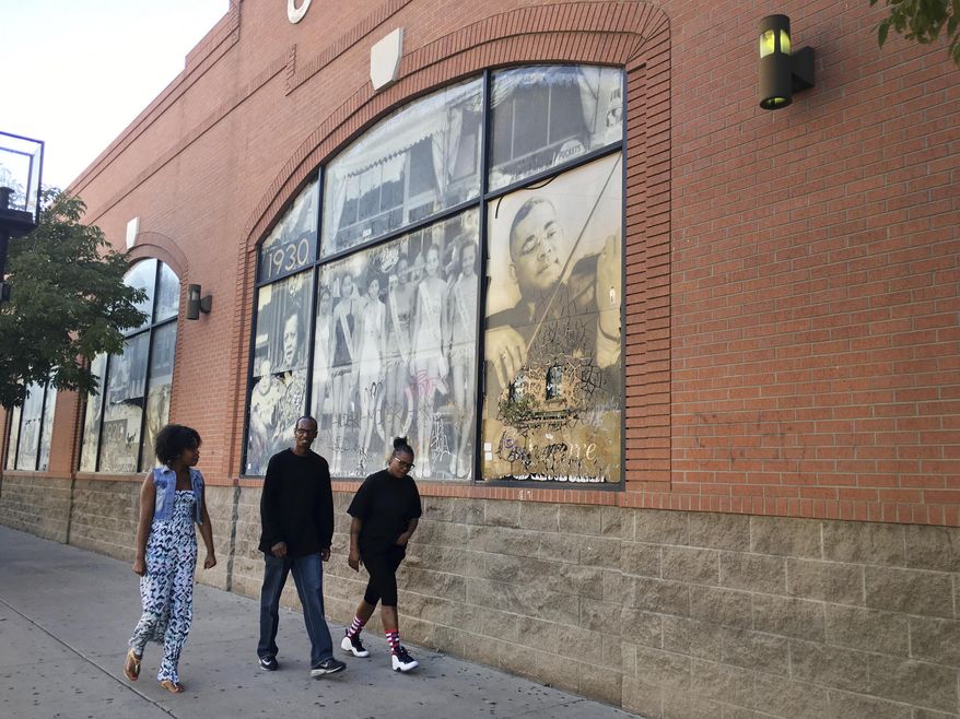 In this Sept. 17, 2016 photo, pedestrians walk past historic photographs celebrating Denver's Five Points, a neighborhood that was called "The Harlem of West," in Denver, Colo. Five Points is where Billie Holiday, Count Basie and Miles Davis performed and novelist Jack Kerouac wrote part of "On The Road." The historic black neighborhood is facing gentrification with new breweries and coffee shops near buildings that once housed jazz clubs and consequential black-owned businesses. (AP Photo/Russell Contreras)