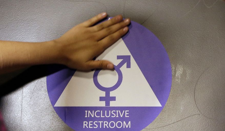 A new sticker is placed on the door at the ceremonial opening of a gender neutral bathroom at Nathan Hale High School in Seattle, in this May 17, 2016, file photo. (AP Photo/Elaine Thompson, File)