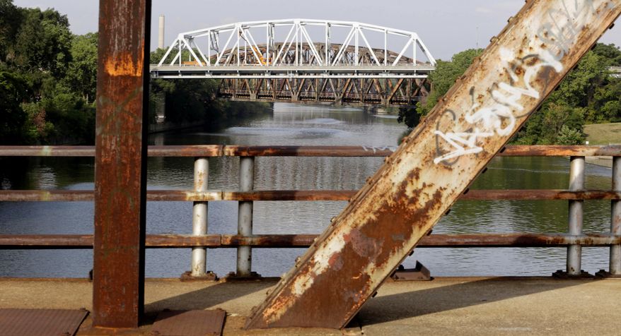 FILE - This Sept. 11, 2013, file photo shows the bridge on Western Avenue over the Cal-Sag Channel framed by the rusted supports of the closed Chatham St. bridge in Blue Island, Ill. The Western Avenue bridge was classified as both "structurally deficient" and "fracture critical" in federal data for 2012. An analysis of Transportation Department data released by the American Road & Transportation Builders Association on Feb. 15, 2017, says more than 55,000 bridges in the U.S. have been deemed structurally deficient. (AP Photo/M. Spencer Green, File)