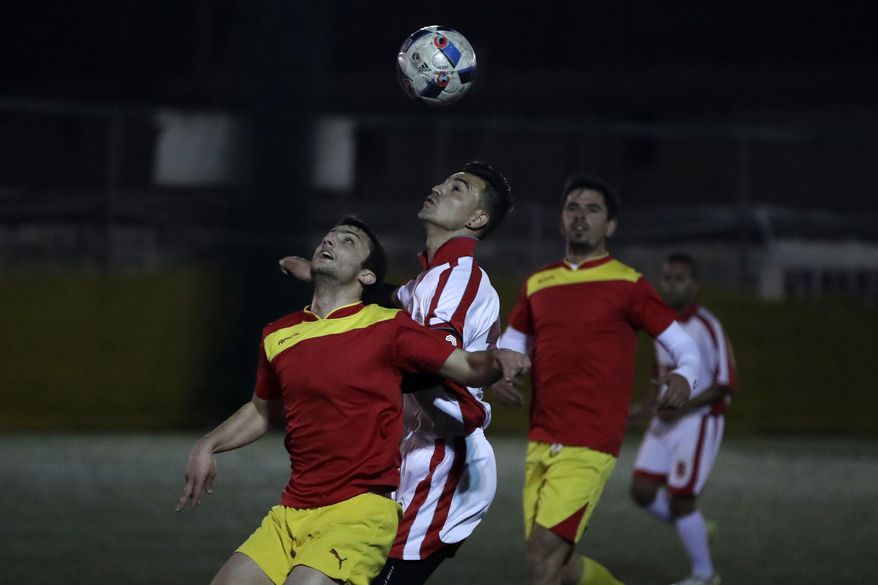 FOR STORY: GREECE TEAM CALLED HOPE - In this Sunday, Feb. 5, 2017, Ahmad Fahim Ahmadi from Afghanistan of Hope Refugee Football Club, center, and a player of 3D Team of Hellenic American University Football Club fight for the ball during a soccer match in western Athens. Former Greek national soccer team goalkeeper Antonis Nikopolidis, who became a national hero in 2004 during the European Cup, is heading a project to help refugees stranded in Greece regain a sense of purpose, working as a team. On weekends they play in an amateur league against teams made up of professional groups like lawyers, telecom workers, and accountants.(AP Photo/Thanassis Stavrakis)