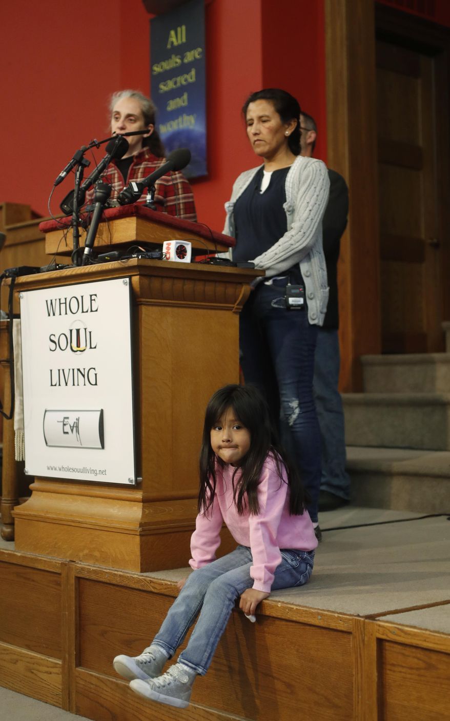 Six-year-old Zuri Vizguerra, front, sits on the edge of the stage as her mother, Jeannette, a Mexican woman seeking to avoid deportation from the United States, speaks during a news conference in the church in which Vizguerra and her children have taken refuge, Wednesday, Feb. 15, 2017, in Denver. U.S. immigration authorities have denied her request to remain in the country. (AP Photo/David Zalubowski)