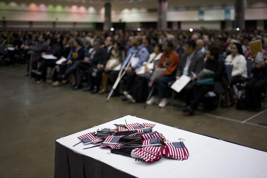 Small U.S. flags are piled on a table as thousands of people attend a naturalization ceremony at the Los Angeles Convention Center, Wednesday, Feb. 15, 2017, in Los Angeles. About 3,000 people took the oath in the morning and more than 3,500 others were expected during an afternoon ceremony, according to U.S. Citizenship and Immigration Services officials. (AP Photo/Jae C. Hong)