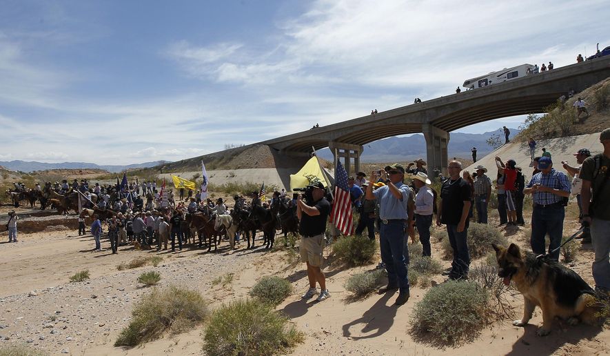 FILE - In this April 12, 2014, file photo, the Bundy family and their supporters gather together under the Interstate 15 highway overpass just outside of Bunkerville, Nev., in order to confront the Bureau of Land Management and demand the release of their impounded cattle. A federal agent testified in Las Vegas, Nev., Wednesday, Feb. 15, 2017, that he saw a "sniper" on a freeway overpass pointing a military-style weapon at him while a crowd of protesters gathered in a dry river bed calling for the government to release Nevada rancher Cliven Bundy's cattle. (Jason Bean/Las Vegas Review-Journal via AP, File)