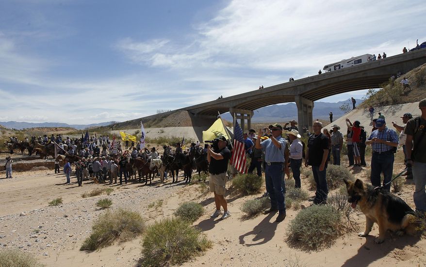FILE - In this April 12, 2014, file photo, the Bundy family and their supporters gather together under the Interstate 15 highway overpass just outside of Bunkerville, Nev., in order to confront the Bureau of Land Management and demand the release of their impounded cattle. A federal agent testified in Las Vegas, Nev., Wednesday, Feb. 15, 2017, that he saw a "sniper" on a freeway overpass pointing a military-style weapon at him while a crowd of protesters gathered in a dry river bed calling for the government to release Nevada rancher Cliven Bundy's cattle. (Jason Bean/Las Vegas Review-Journal via AP, File)