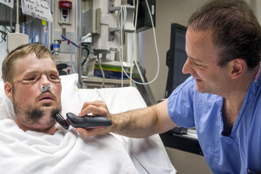 In this July 3, 2016 photo provided by the Mayo Clinic, Dr. Samir Mardini shaves the face of his patient, Andy Sandness, days after leading a team that performed the first face transplant surgery at the hospital. Over the years, the two say they've become as close as brothers. (Eric M. Sheahan/Mayo Clinic via AP)