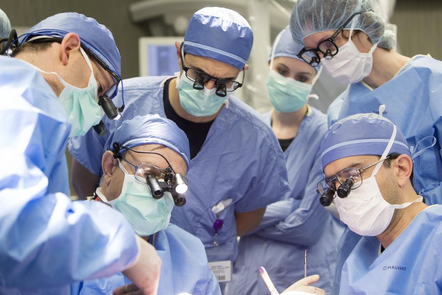 In this June 13, 2016 photo provided by the Mayo Clinic, a medical team performs a face transplant surgery at the medical center in Rochester, Minn. It took about 24 hours to procure the donor's face, which involved taking bone, muscle, skin and nerves, and almost the same time to prepare the recipient. His entire face was rebuilt below his eyes, taking an additional 32 hours. The medical team rotated, taking four-hour breaks through the weekend. (Eric M. Sheahan/Mayo Clinic via AP)