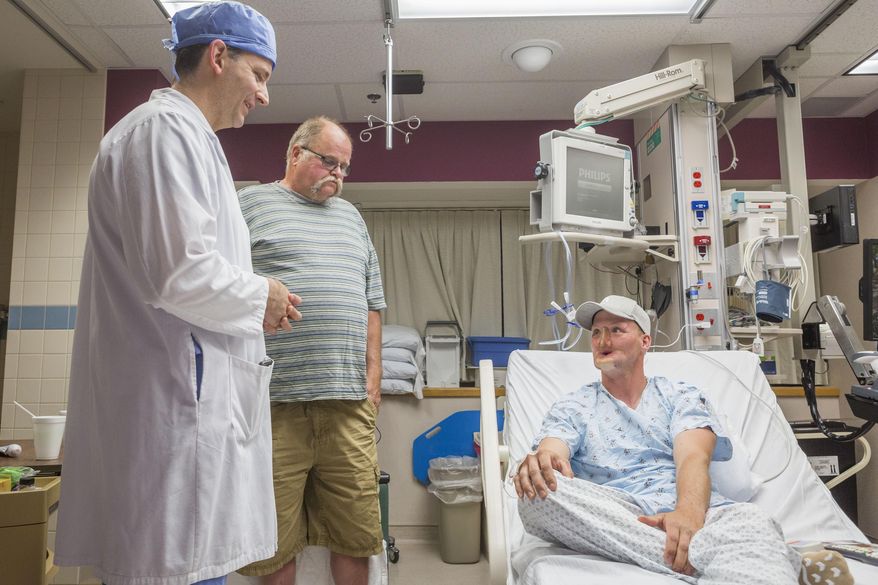 In this June 10, 2016 photo provided by the Mayo Clinic, Andy Sandness, right, talks with his father, Reed Sandness, and Dr. Samir Mardini, left, before Andy's face transplant procedure at the Mayo Clinic in Rochester, Minn. In the process leading up to the surgery, Mardini tried to temper his patient's enthusiasm. "Think very hard about this," he said. Only a few dozen transplants have been done around the world, and he wanted Andy to understand the risks and the aftermath: a lifelong regimen of anti-rejection drugs. But Sandness could hardly contain himself. "How long until I can do this?" he asked. (Eric M. Sheahan/Mayo Clinic via AP)