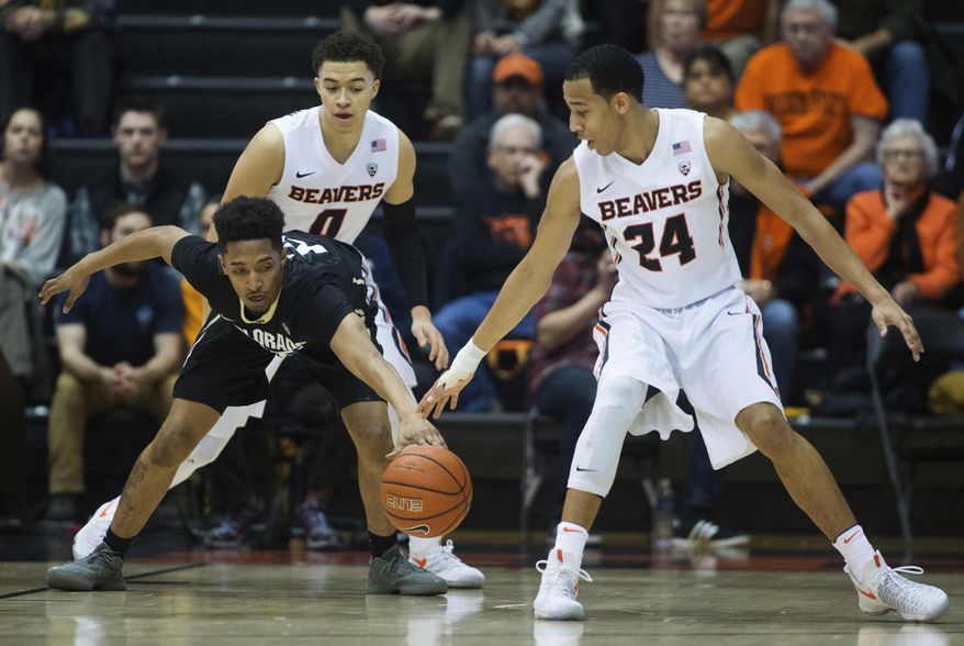Colorado's Dominique Collier, left, reaches for the ball while being guarded by Oregon State's JaQuori McLaughlin (0) and Kendal Manuel (24) during the first half of an NCAA college basketball game in Corvallis, Ore., Thursday, Feb. 16, 2017. (AP Photo/Timothy J. Gonzalez)