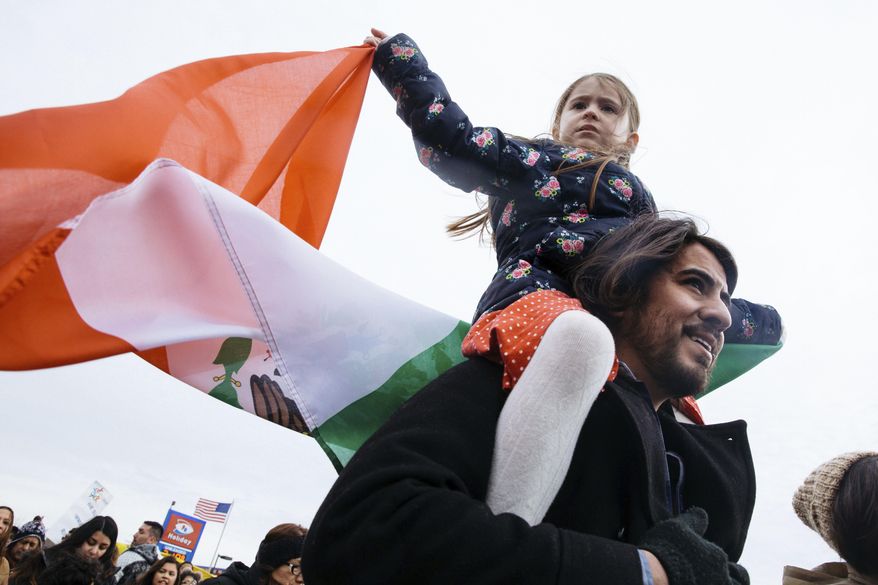 Eva Marquez, 6, waves the flag of Mexico while riding on her father Marco's shoulders during a protest for a +Day Without Immigrants" protest Thursday, Feb. 16, 2017, in St. Paul, Minn. It was part of a nationwide rally designed to show how important immigrants are to daily life. (Evan Frost/Minnesota Public Radio via AP)