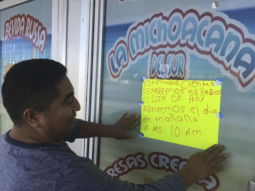 Jose Lopez, 38, owner of La Michoacana Del Sur restaurant in Albuquerque's South Valley neighborhood, puts up a sign on Thursday, Feb. 16, 2017, in Albuquerque, N.M., announcing that his Mexican restaurant was closed in support of a national protest. Immigrants around the U.S. stayed home from work and school Thursday to demonstrate how important they are to America's economy and its way of life, and many businesses closed in solidarity, in a nationwide protest called A Day Without Immigrants. (AP Photo/Russell Contreras)