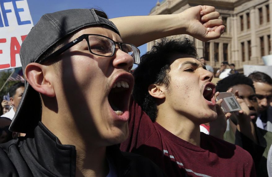 Andres Mijares, left, and Joseph Cruz, right, join others during a march and rally during an immigration protest, Thursday, Feb. 16, 2017, in Austin, Texas. Immigrants around the U.S. stayed home from work and school Thursday to demonstrate how important they are to America's economy and way of life, and many businesses closed in solidarity, in a nationwide protest called A Day Without Immigrants. (AP Photo/Eric Gay)