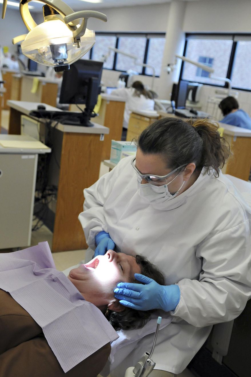 FILE - In this Dec. 4, 2009 file photo, dental hygienist Jodi Hager performs an oral exam on staff member Clare Larkin during a test at Normandale Community College in Edina, Minn. Several states are considering bills that would create a new midlevel position in dentistry called dental therapists or advanced dental hygiene practitioners. They can perform common procedures such as filling cavities or pulling teeth, though more complex procedures would still be left with dentists. (AP Photo/Dawn Villella, File)