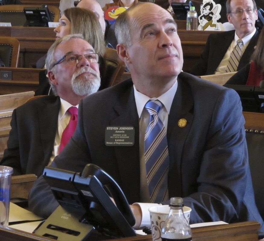 Kansas state Reps. John Barker, left, R-Abilene, and Steven Johnson, right, R-Assaria, watch one of the House's electronic vote-tallying boards as the chamber approves a bill increasing personal income taxes to help balance the state budget, Thursday, Feb. 16, 2017, at the Statehouse in Topeka, Kan. Johnson is chairman of the House Taxation Committee, which drafted the measure (AP Photo/John Hanna)