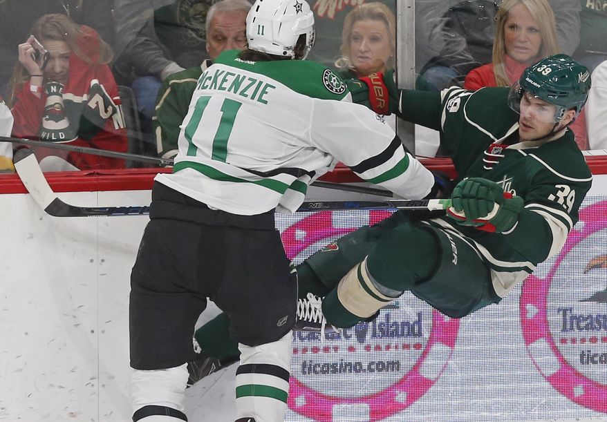 Minnesota Wild&#x27;s Nate Prosser, right, gets upended along the boards from a check by Dallas Stars&#x27; Curtis McKenzie as a fan, left, cringes at the hit during the first period of an NHL hockey game Thursday, Feb. 16, 2017, in St. Paul, Minn. (AP Photo/Jim Mone)