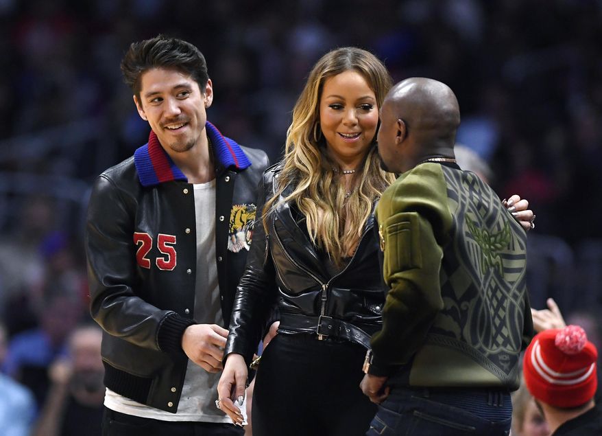 Singer Mariah Carey, center, talks with boxer Floyd Mayweather Jr., right, as Bryan Tanaka standsnear by during the second half of an NBA basketball game between the Atlanta Hawks and the Los Angeles Clippers on Wednesday, Feb. 15, 2017, in Los Angeles. The Clippers won 99-84. (AP Photo/Mark J. Terrill)