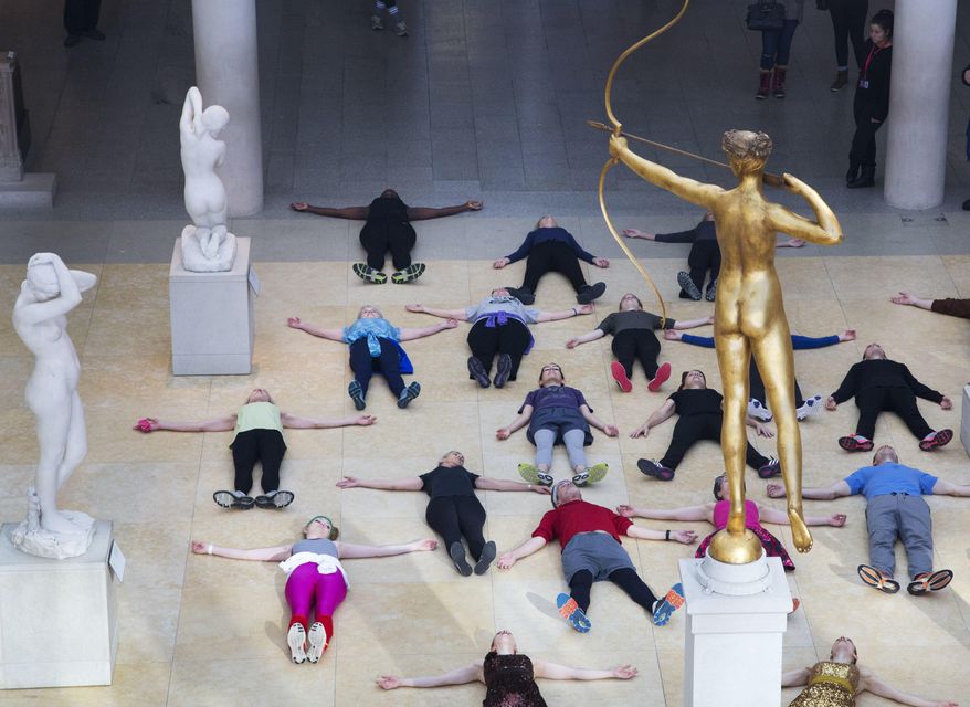 In this Feb. 10, 2017 photo, an exercise group lies down at the feet of a bronze statue of Diana, the Roman goddess of the hunt, after a workout at the Metropolitan Museum of Art in New York. The museum has been hosting lively workout sessions amid its prized masterpieces. (AP Photo/Mark Lennihan)