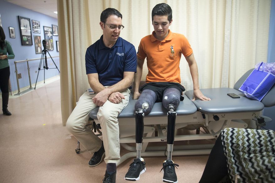 In this Monday, Feb 13, 2017 photo, prosthetist David Rotter, left, of Scheck & Siress, coaches Vidal Lopez before he takes a walk down the hallway in his new prosthetic legs at the University of Illinois at Chicago Hospital, in the Near West Side neighborhood. Heather Abbott, a survivor of the Boston Marathon bombing and founder of The Heather Abbott Foundation, teamed up with Scheck & Siress, a Chicago based prosthetic firm to provide Lopez with new customizable prosthetic legs. Vidal was born in Chicago but grew up in Mexico. A car crash involving a tractor trailer in July 2016, left him without his legs. He wrote to the Heather Abbott Foundation with hopes to receive a grant to help him pay for the prosthetic legs that he needed. Heather was touched by his story and decided to provide Vidal with the financial support he needed to secure his future. (Alyssa Pointer/Chicago Tribune via AP)