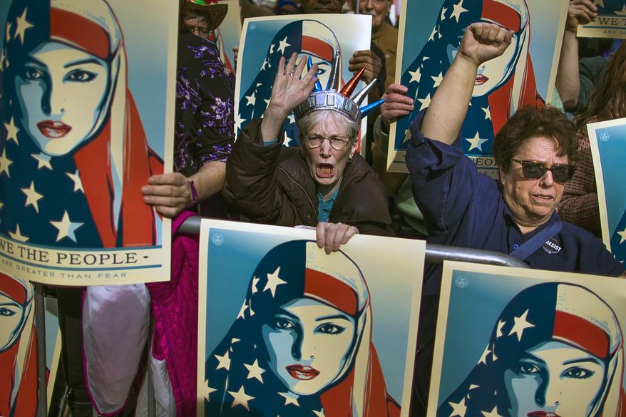 People carry posters during a rally against President Donald Trump's executive order banning travel from seven Muslim-majority nations, in New York's Times Square, Sunday, Feb. 19, 2017. (AP Photo/Andres Kudacki)