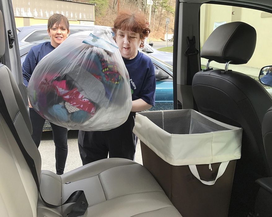 In this Wednesday, Feb. 15, 2017 photo, taken outside the Disability Action Center in Fairmont, W.Va., volunteer laundry assistant Amy Tatterson, right, and job coach Chrissy Heldreth load the van for a delivery. The Marion County Disability Action Center (DAC) continues to create new programs to benefit many members of the community. Feel Good Laundry Service lends a hand to residents with the pickup and delivery service. (Kelsie LeRose/Times-West Virginian, via AP)