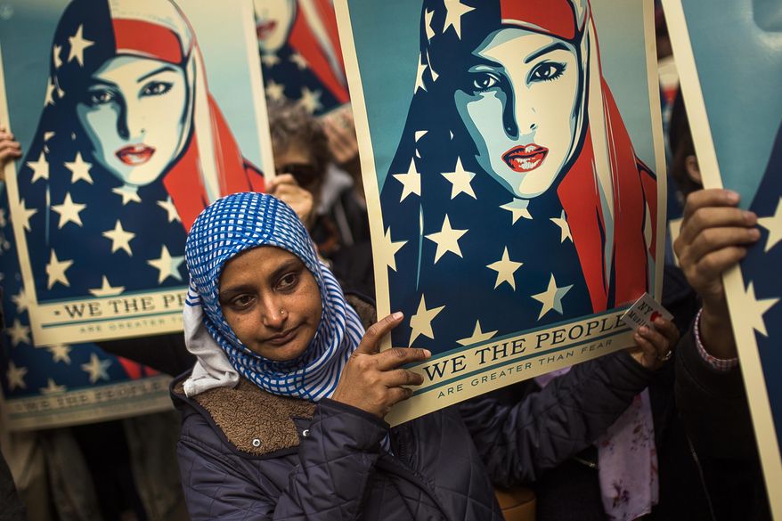 People carry posters during a rally against President Donald Trump's executive order banning travel from seven Muslim-majority nations, in New York's Times Square, Sunday, Feb. 19, 2017. (AP Photo/Andres Kudacki)