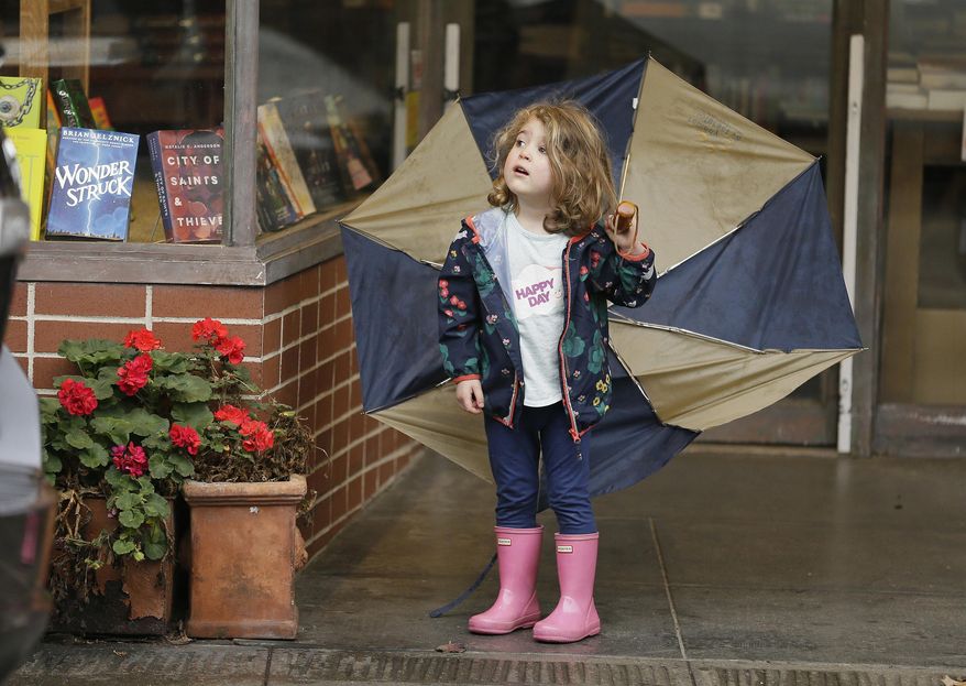 Three-year-old Emerson Cassidy takes cover from the rain in a storefront entryway Monday, Feb. 20, 2017, in San Anselmo, Calif. Heavy downpours are swelling creeks and rivers and bringing threats of flooding in California's already soggy northern and central regions. The National Weather Service map shows floods, snow and wind advisories for the northern part of the state. (AP Photo/Eric Risberg)