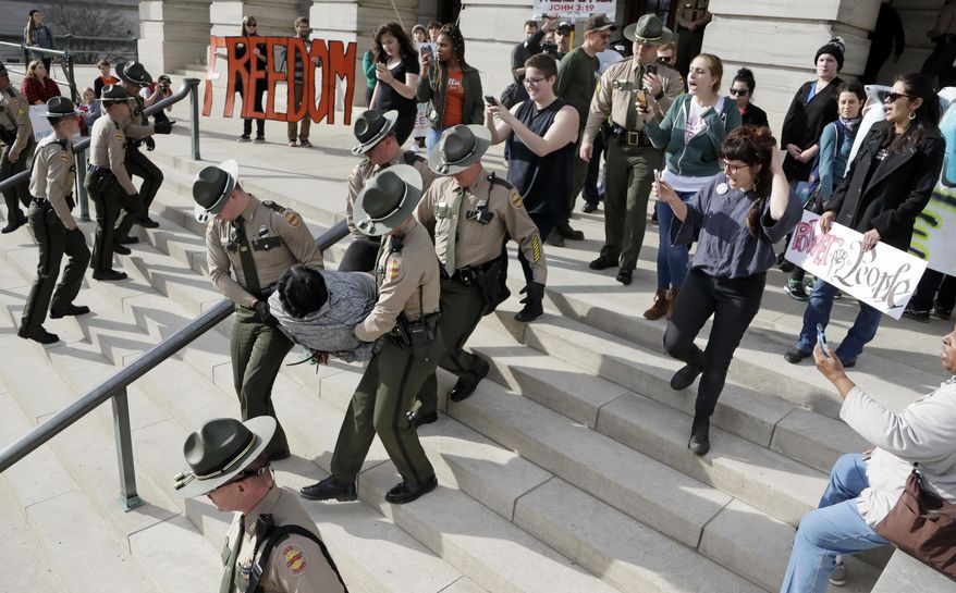 FILE - In this Friday, Jan. 20, 2017, file photo, a protester is carried away from the state Capitol building in Nashville, Tenn. Protests around the state Capitol in Nashville have some Republicans calling for a crackdown on demonstrators and for resurrecting more stringent security requirements for entering the legislative office complex. Democrats are pushing back against those calls, arguing that access to the legislators shouldn’t be curtailed only because many of the protesters oppose the policies of Republican President Donald Trump on issues including immigration, race, abortion and LGBT rights. (AP Photo/Mark Humphrey, File)