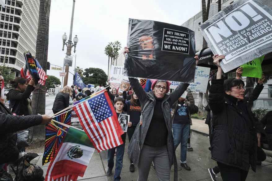 Protesters march down a street past Los Angeles City Hall on Monday, Feb. 20, 2017. Demonstrators gathered to express their opposition to President Donald Trump and take part in a ''Not My President's Day'' rally. (AP Photo/Richard Vogel)