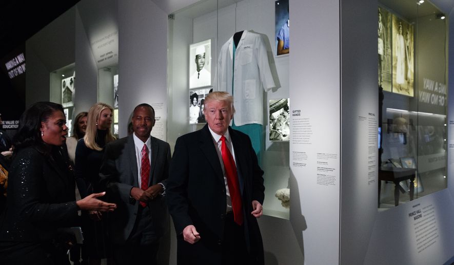 President Donald Trump walks with Housing and Urban Development Secretary-designate Dr. Ben Carson, as they pass a exhibit honoring Carson during a tour of the National Museum of African American History and Culture, Tuesday, Feb. 21, 2017, in Washington. (AP Photo/Evan Vucci)