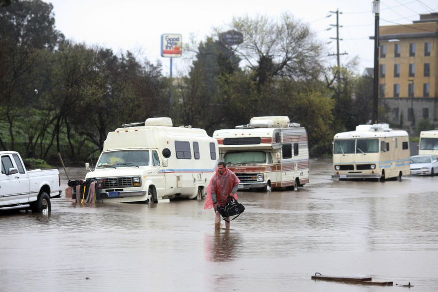 A man who lives in his RV, which was parked in the 300 block of Griffith Street in Salinas, Calif., walks through the flooded street on Mon., Feb. 20, 2016. ~ OUT: MONTEREY HERALD, SALINAS CALIFORNIAN, SANTA CRUZ SENTINEL, MONTEREY COUNTY TELEVISION NEWSMonday, Feb. 20, 2017, in Salinas, Calif. Forecasters issued flash flood warnings Monday throughout the San Francisco Bay Area and elsewhere in Northern California as downpours swelled creeks and rivers in the already soggy region. (Nic Coury/Monterey County Weekly via AP)