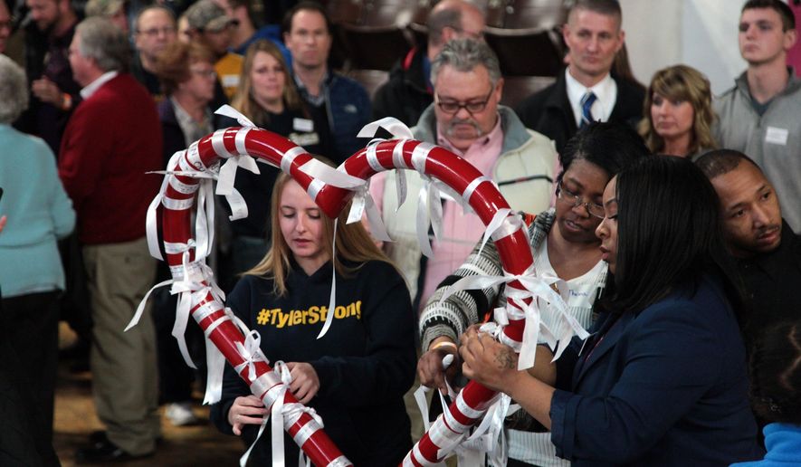 Tiana Carruthers, right, ties a ribbons to a metal heart during a vigil at the Wings Event Center in Kalamazoo, Mich., on Monday, Feb. 20, 2017. The 20th marked the one-year anniversary of the February 2016 shooting which killed six people in Kalamazoo County. (Jake Green/Kalamazoo Gazette-MLive Media Group via AP)