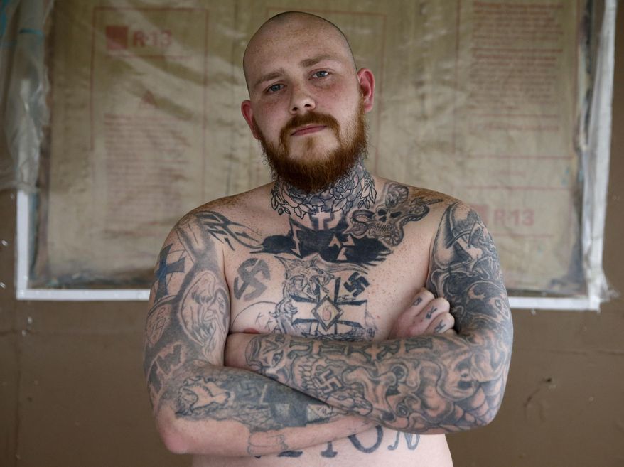 In this Thursday, Jan. 12, 2017 photo, Shane Johnson displays some of his tattoos as he poses in his home in Tippecanoe, Ind. Johnson was born into extremism is in the process of covering some of his racist tattoos with new ones and wears long sleeves to hide remnants of his past he regrets. His father and many of his father's relatives were part of the Klan, he said, so there was only one real way for him to go as a youth. (AP Photo/Michael Conroy)