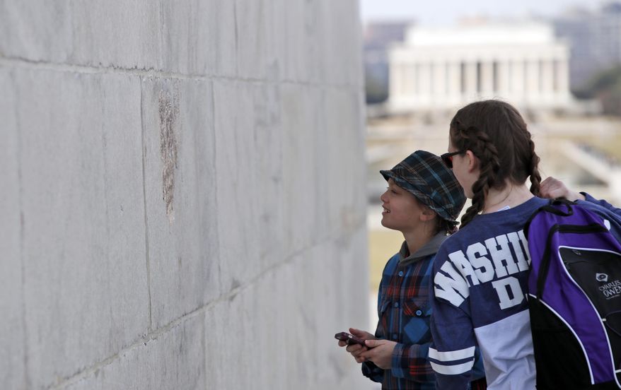 With the Lincoln Memorial in the background, people look at graffiti on the Washington Monument, Tuesday, Feb. 21, 2017, in Washington. U.S. Park Police spokeswoman Sgt. Anna Rose said that the messages written in permanent marker were discovered over the holiday weekend at the Lincoln Memorial, the Washington Monument and the World War II Memorial. (AP Photo/Alex Brandon)
