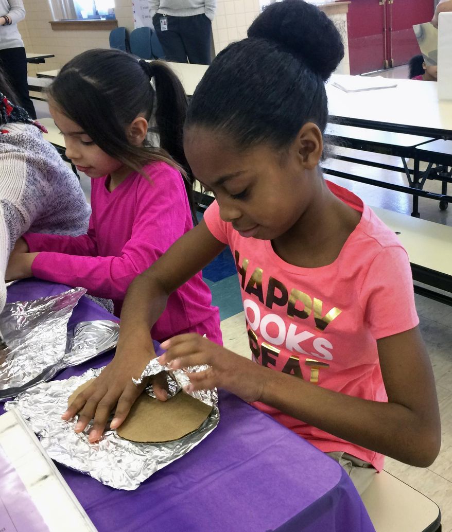 In this Feb. 14, 2017 photo, fourth-graders Jazyre Guzman, left, and Zariah Thomas, right, create tin foil hearts as part of the Love Wins Friendship Day at Chamberlain Elementary school in New Britain, Conn. The program is designed to deal with the problem of social isolation and teach students about empathy. (AP Photo/Pat Eaton-Robb)
